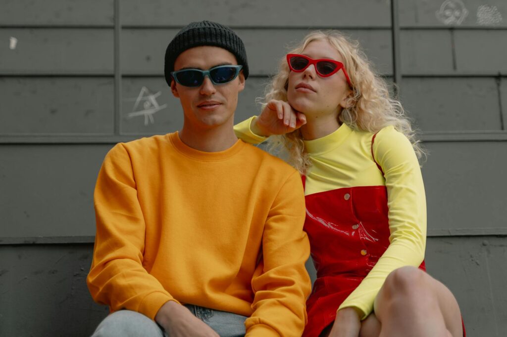 young couple in trendy outfits sitting outside