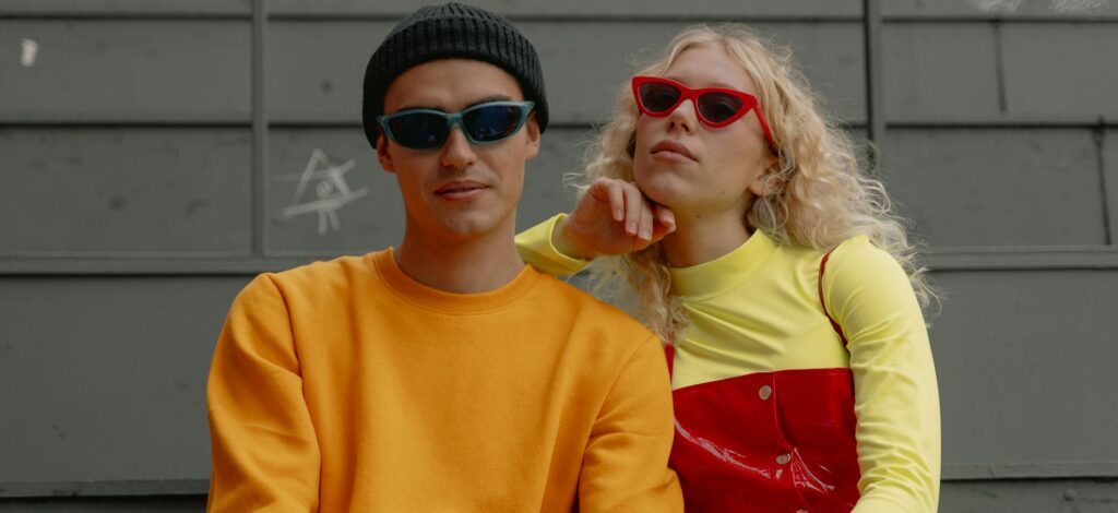 young couple in trendy outfits sitting outside